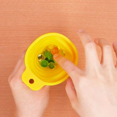 4. ろうとからビーズを押し込んで、水風船に詰めていく